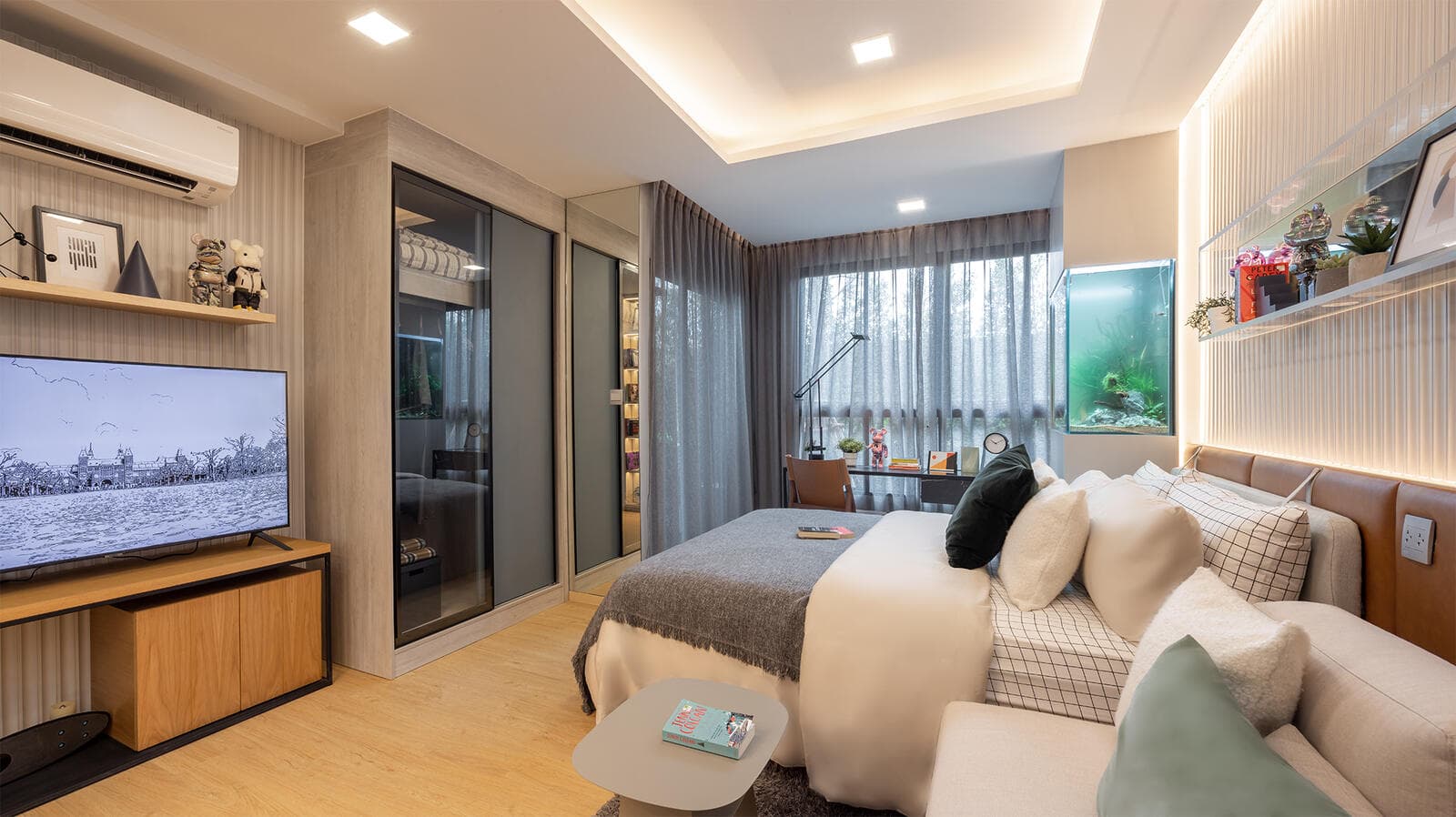 Show unit at Atmoz Kanaal Rangsit photographed from the entrance: bed, sofa, wall-mounted television and mirrored wardrobe with a glazed wall onto the balcony