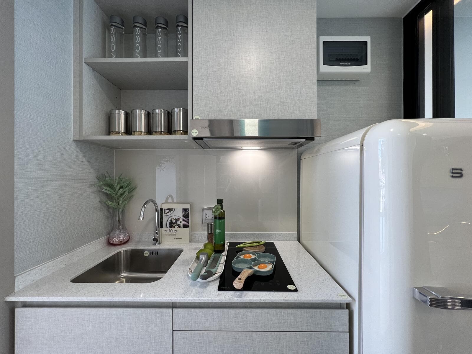 Built-in kitchen pantry of a 24.10 sq.m. one-bedroom show unit at Atmoz Oasis Onnut, with a stone worktop, sink, induction hob, extractor hood and refrigerator