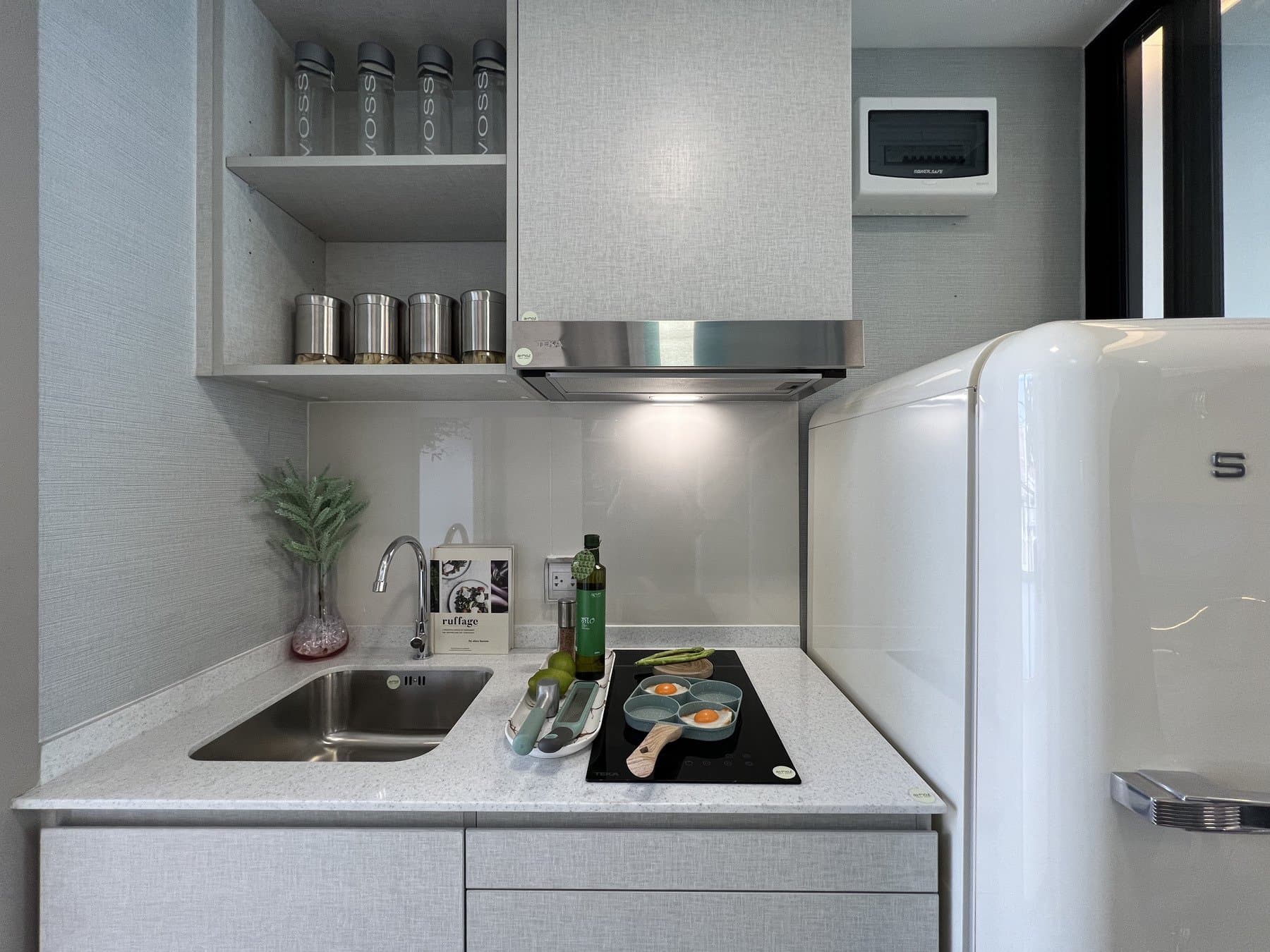 Compact kitchen at Atmoz Oasis Onnut with a white retro-style fridge, an extractor hood and canisters on the overhead shelf