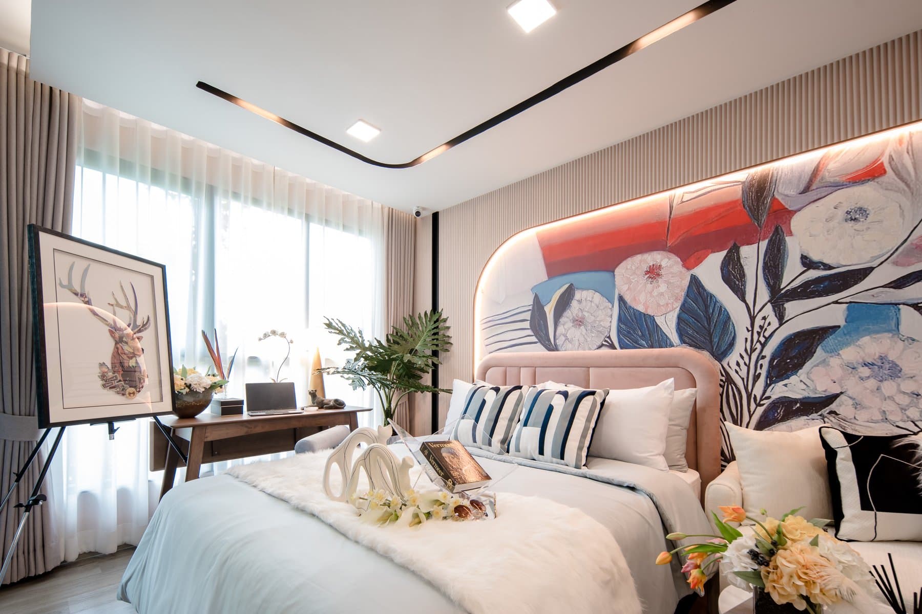 Bed in a furnished show unit at Atmoz Palacio, set against a large floral headboard panel with a curved cove light above