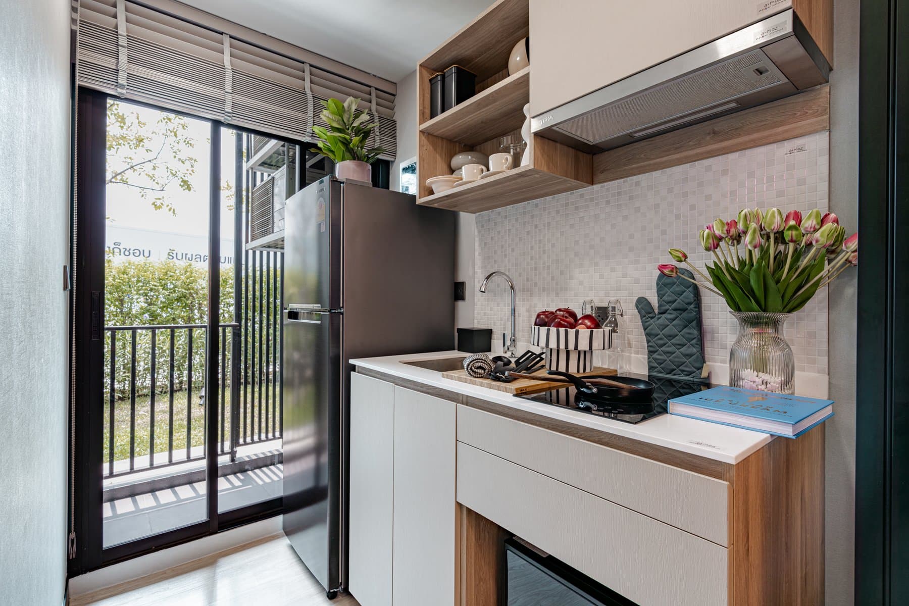 Kitchen run in a furnished show unit at Atmoz Season Ladkrabang, with an extractor, a coffee machine and tulips on the counter beside the balcony door