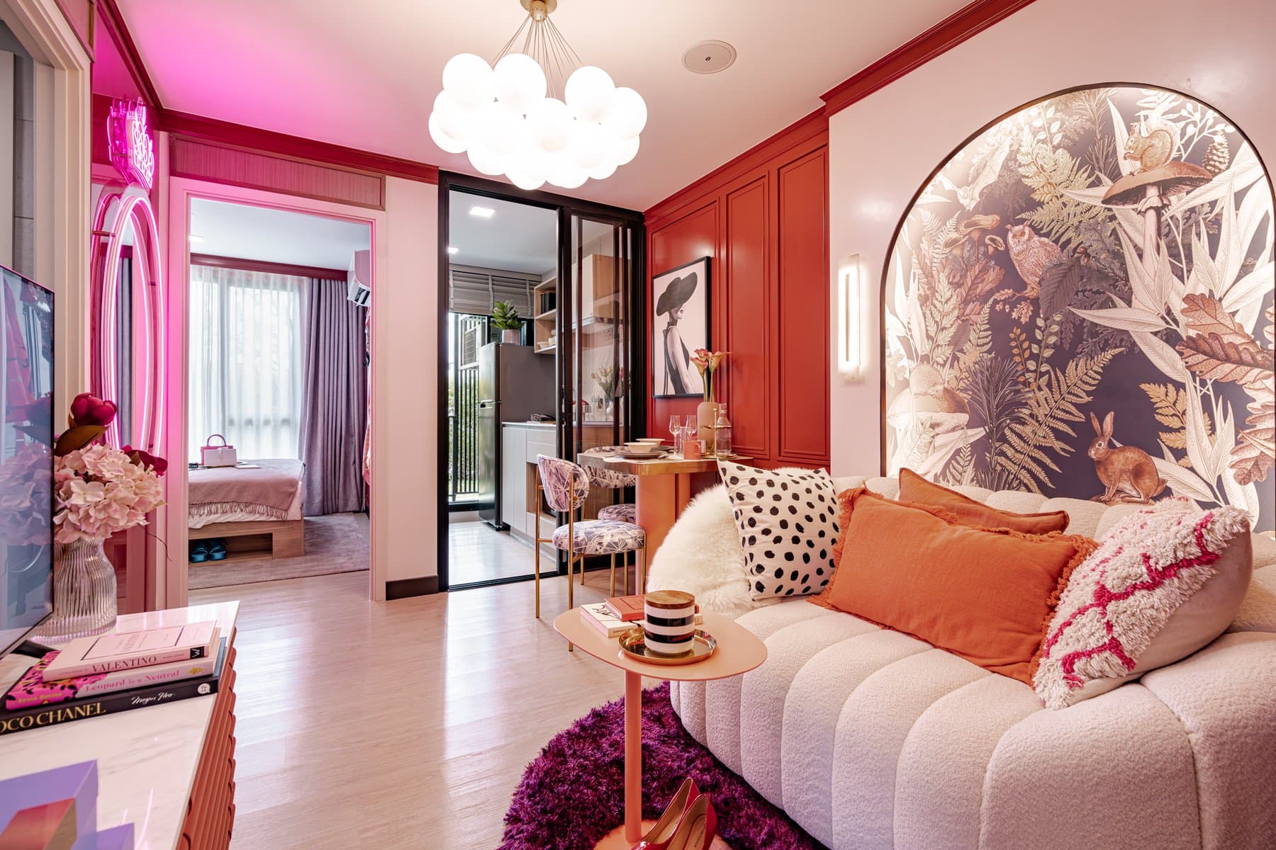 Living area of a furnished show unit at Atmoz Season Ladkrabang, with a blush curved sofa, a chandelier and a circular mural behind