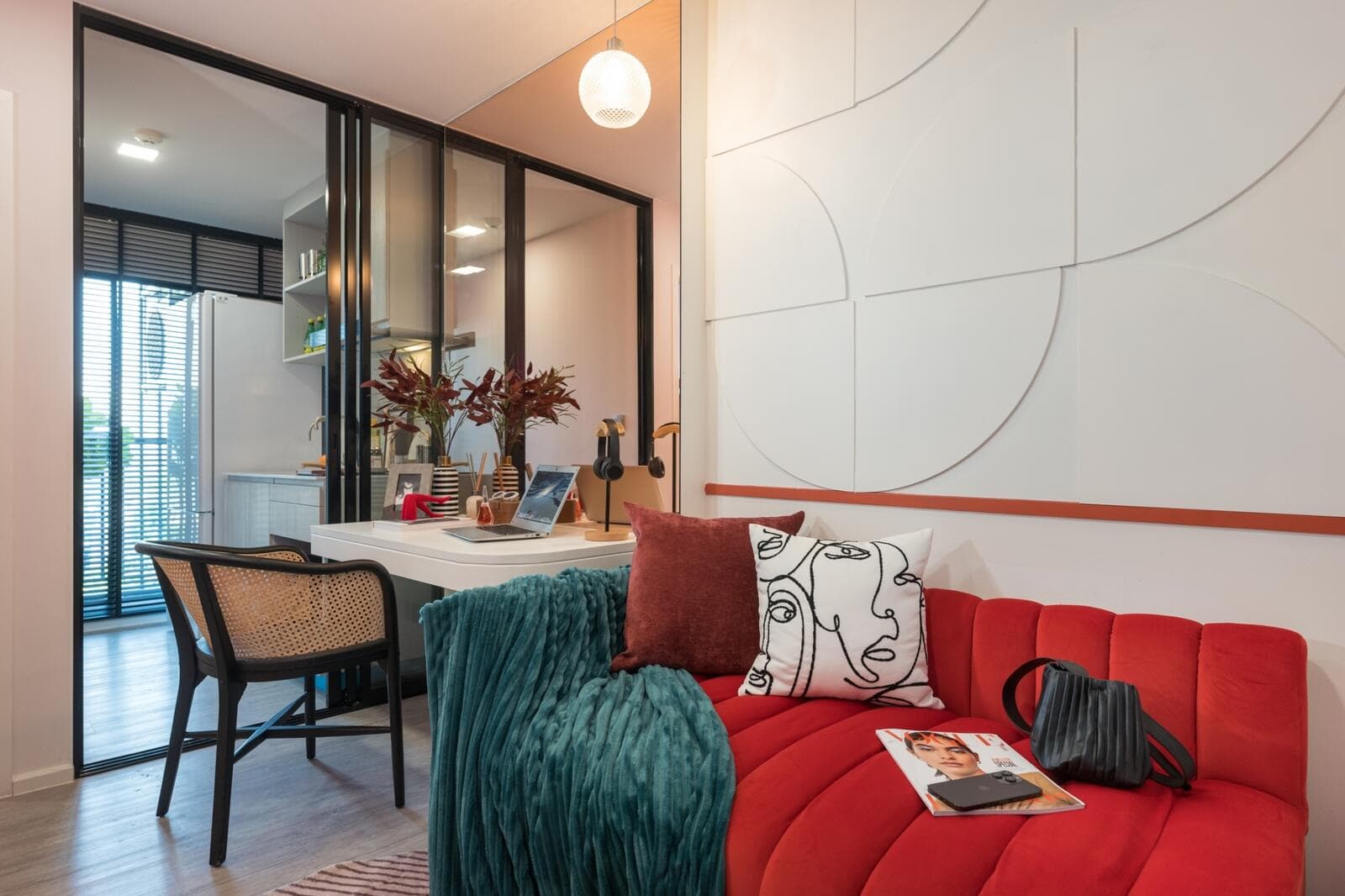 Show unit living area of a 1 Bedroom Exclusive suite at Atmoz Tropicana Bangna, with a fabric sofa, built-in study counter and glazed partition to the kitchen