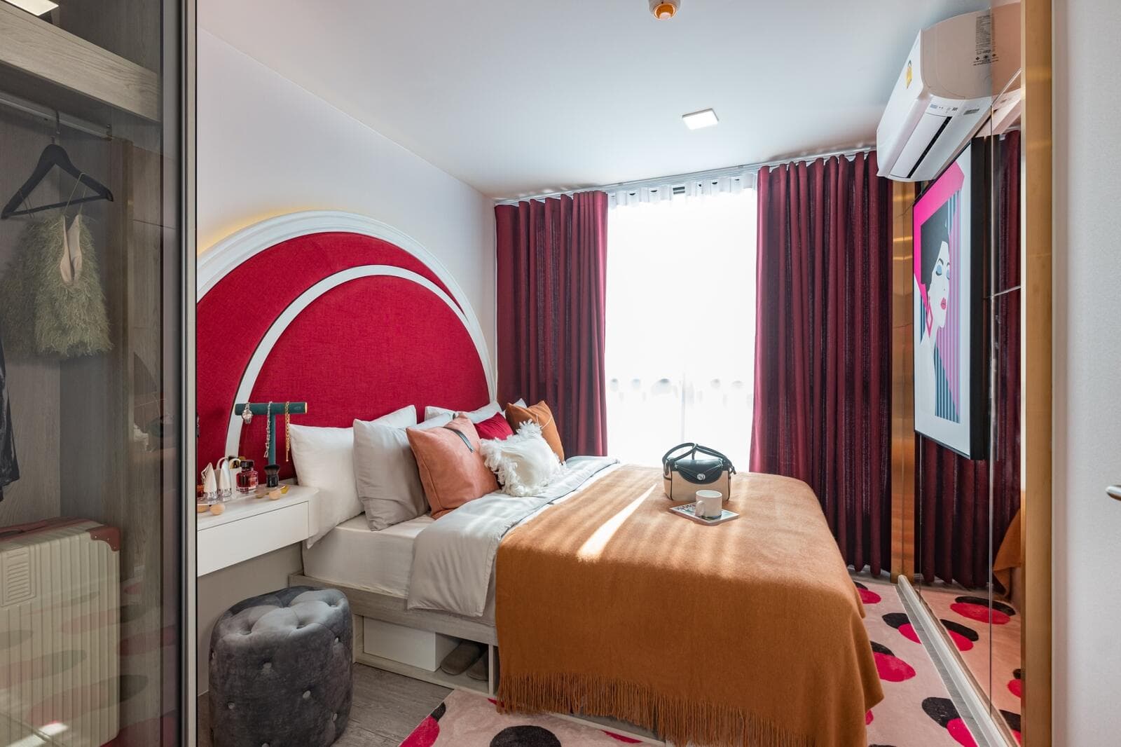 Show unit bedroom of a 1 Bedroom Exclusive suite at Atmoz Tropicana Bangna, with an upholstered headboard, fitted wardrobe, wall-mounted air conditioner and curtained window