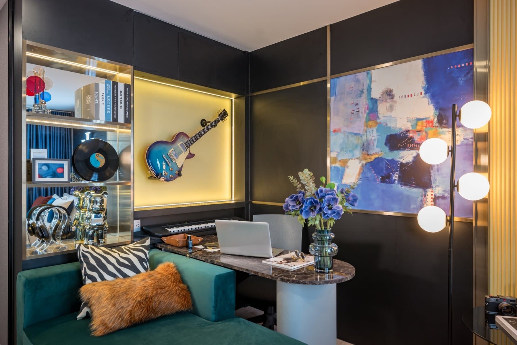 Study and music corner in a furnished show unit at Atmoz Tropicana Bangna, with a teal daybed, a backlit display shelf of records and a guitar on the wall