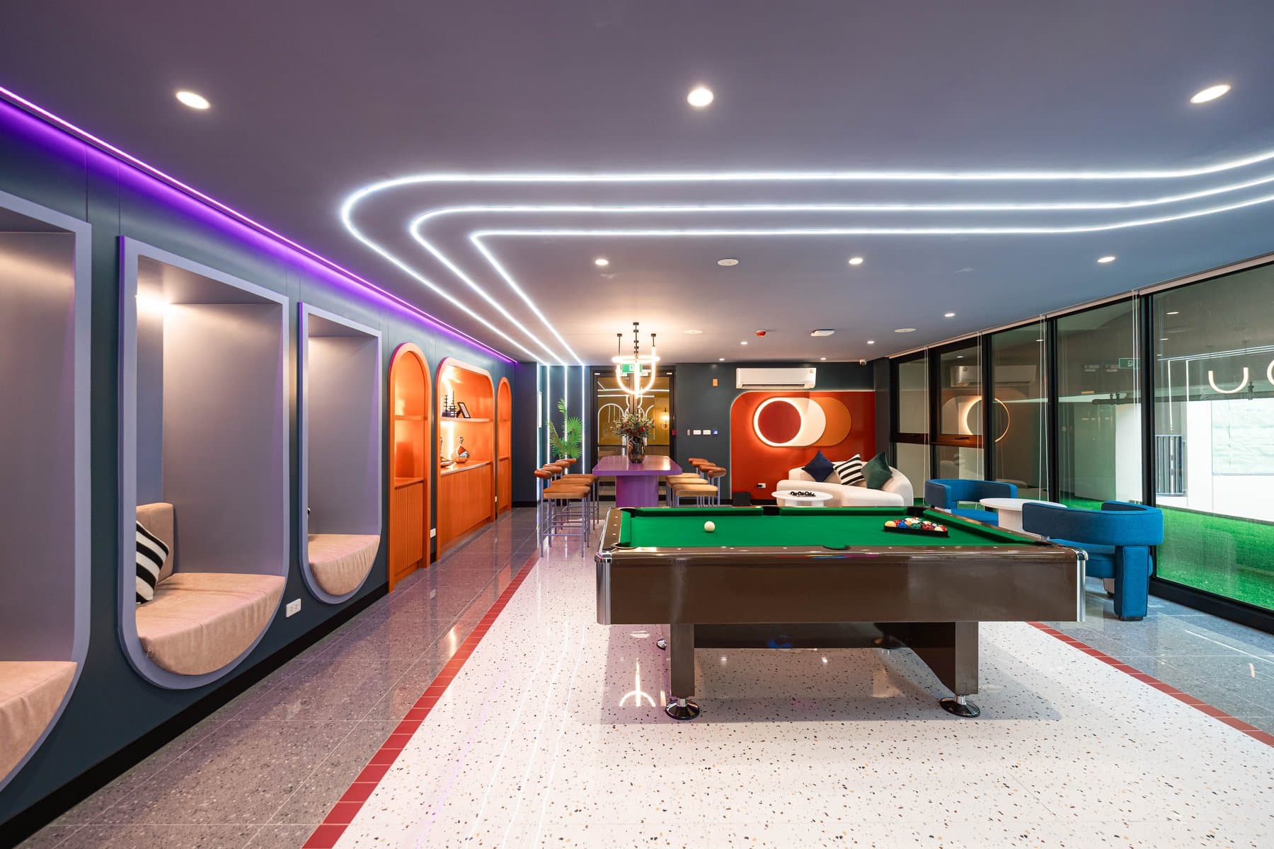 Games room at Kave COCO Bangsaen with a full-size pool table, a green feature wall and a curved corridor lit by linear ceiling strips