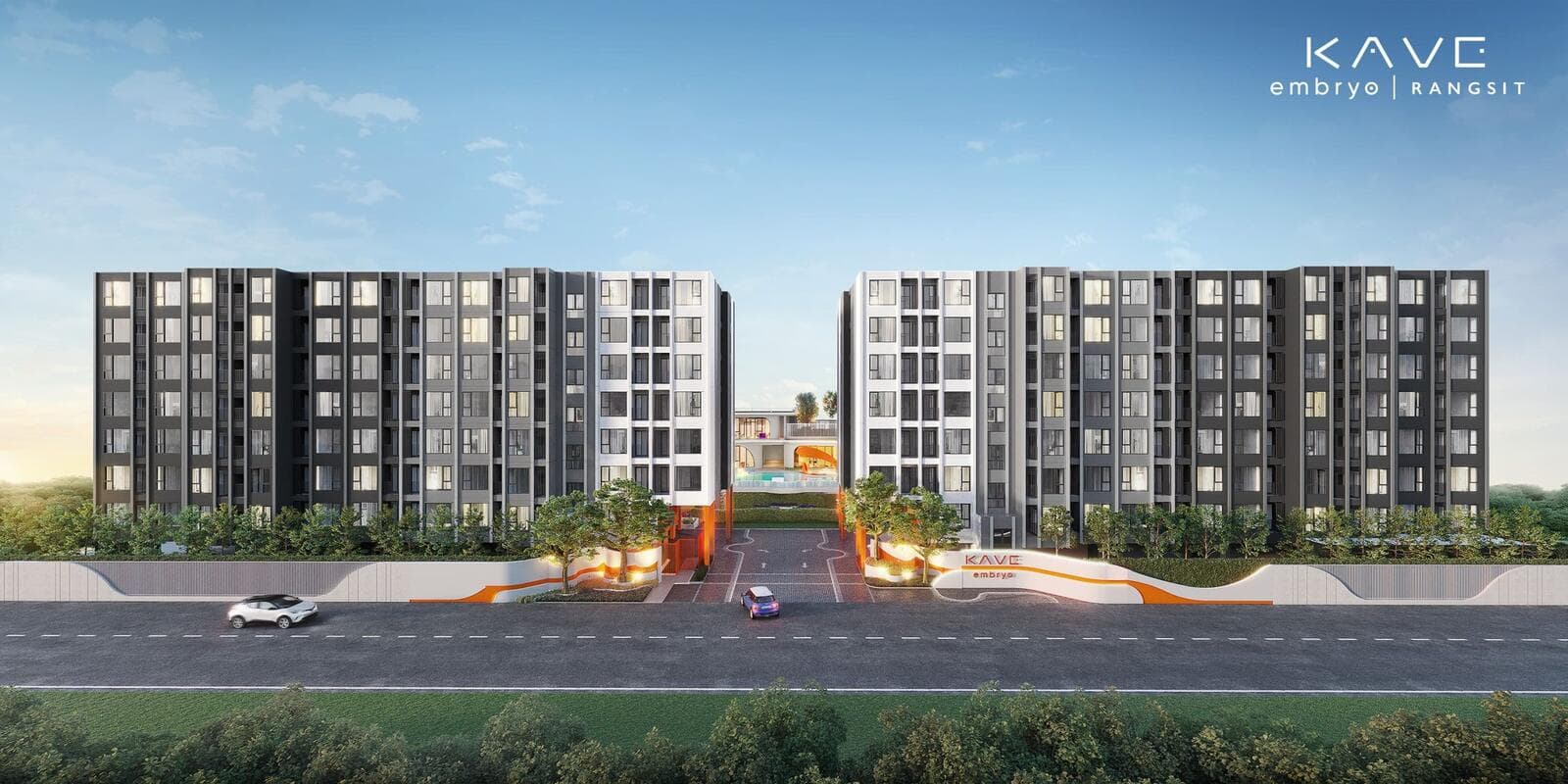 KAVE Embryo Rangsit seen from the street: two eight-storey residential buildings in white and charcoal grey flanking the landscaped entrance driveway at dusk