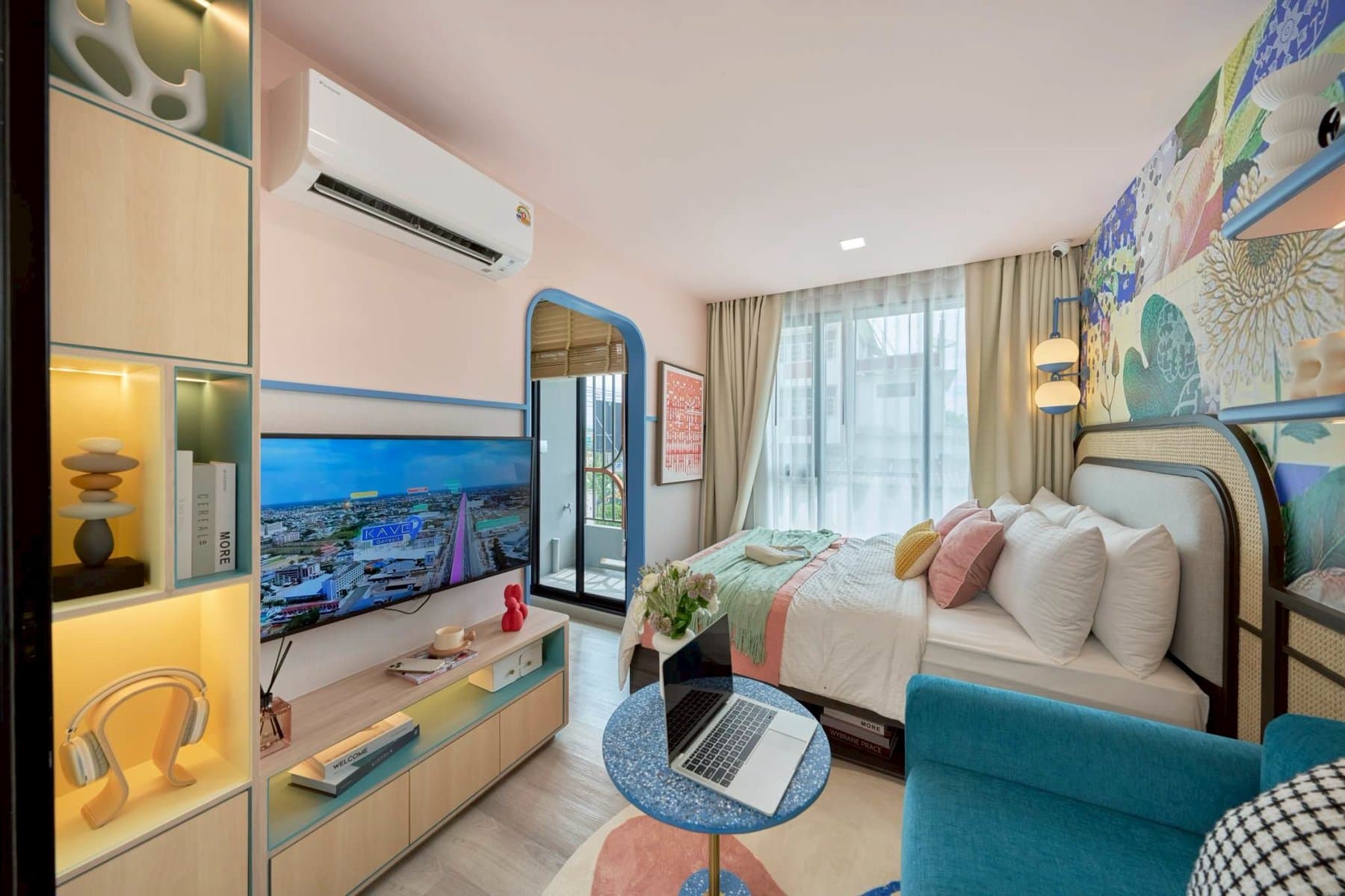 Full length of the One Bedroom show unit at Kave Genesis, from the mirrored wardrobe past the television and teal armchair to the curtained window