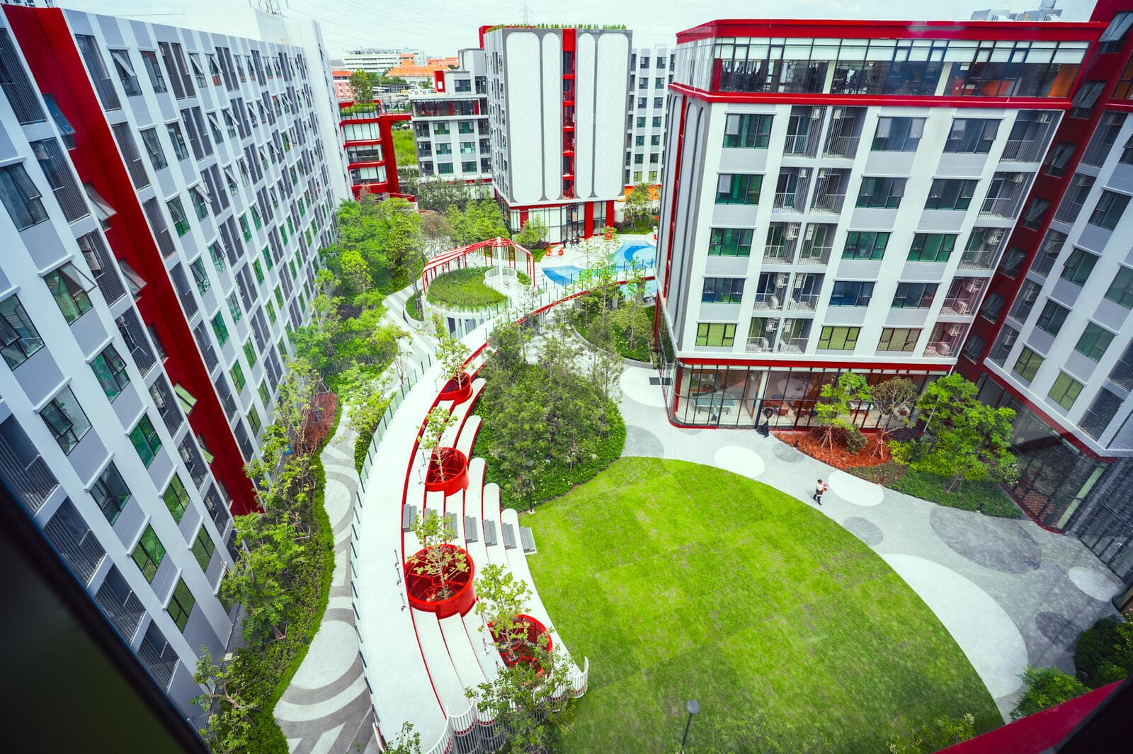 Landscaped courtyard lawn, curved walkway and terraced garden seating between the residential buildings at Kave Wonderland