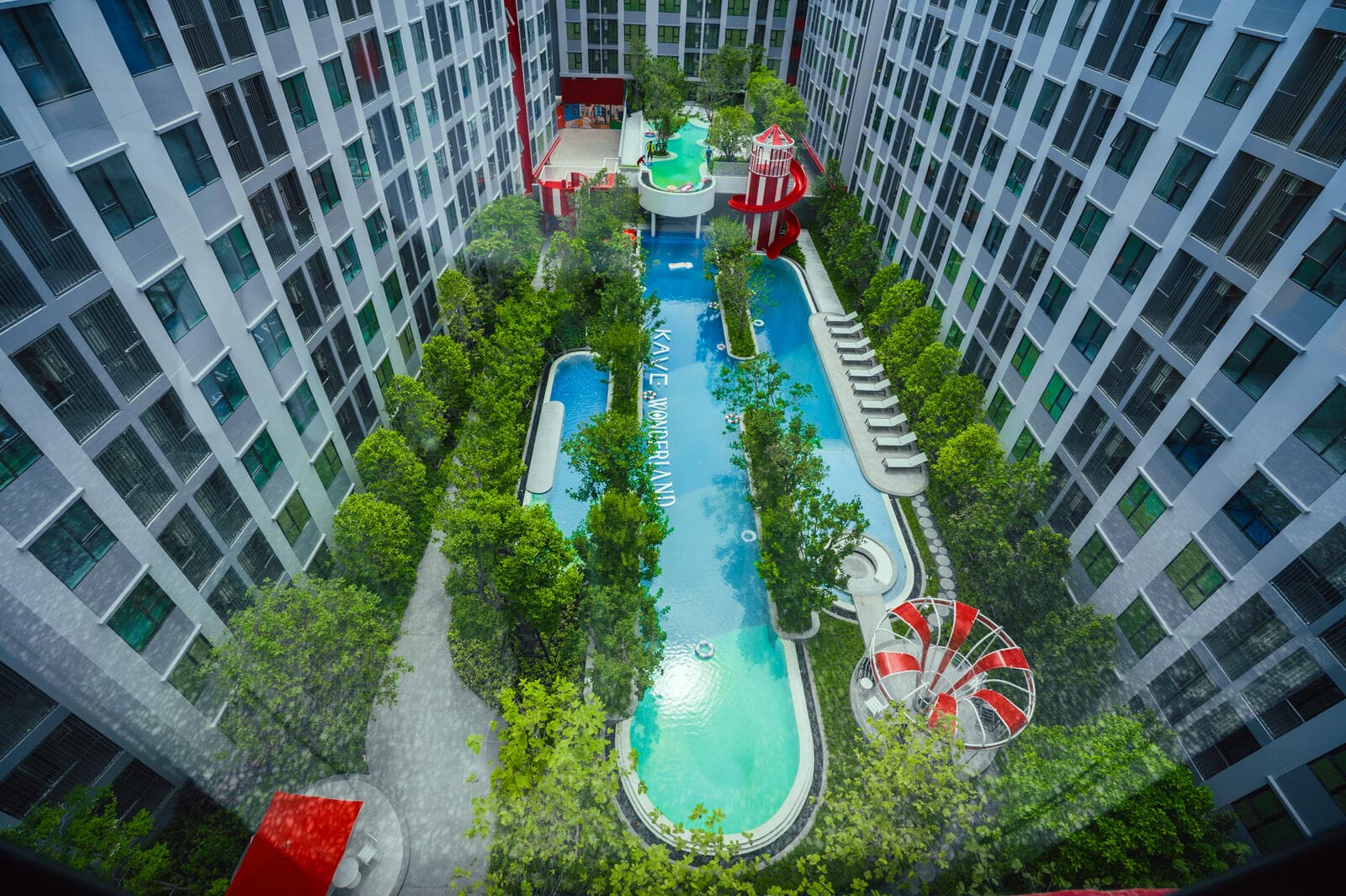 The long courtyard pool and planted gardens at Kave Wonderland seen looking down from an upper residential floor