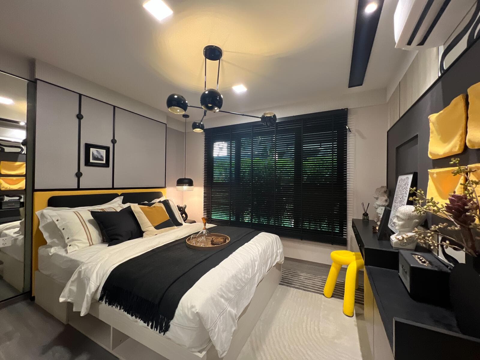Show unit bedroom at Kave Wonderland with a panelled headboard wall, built-in storage, black venetian blinds and a mirrored wardrobe