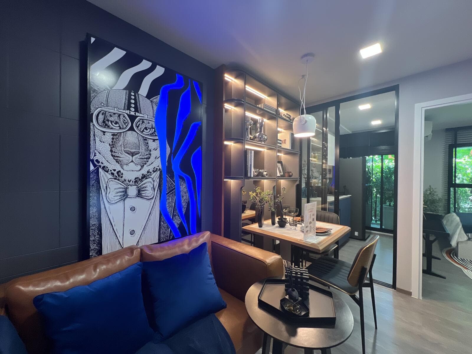Show unit living and dining area at Kave Wonderland with a lit display shelving wall, leather bench seating and a compact dining table