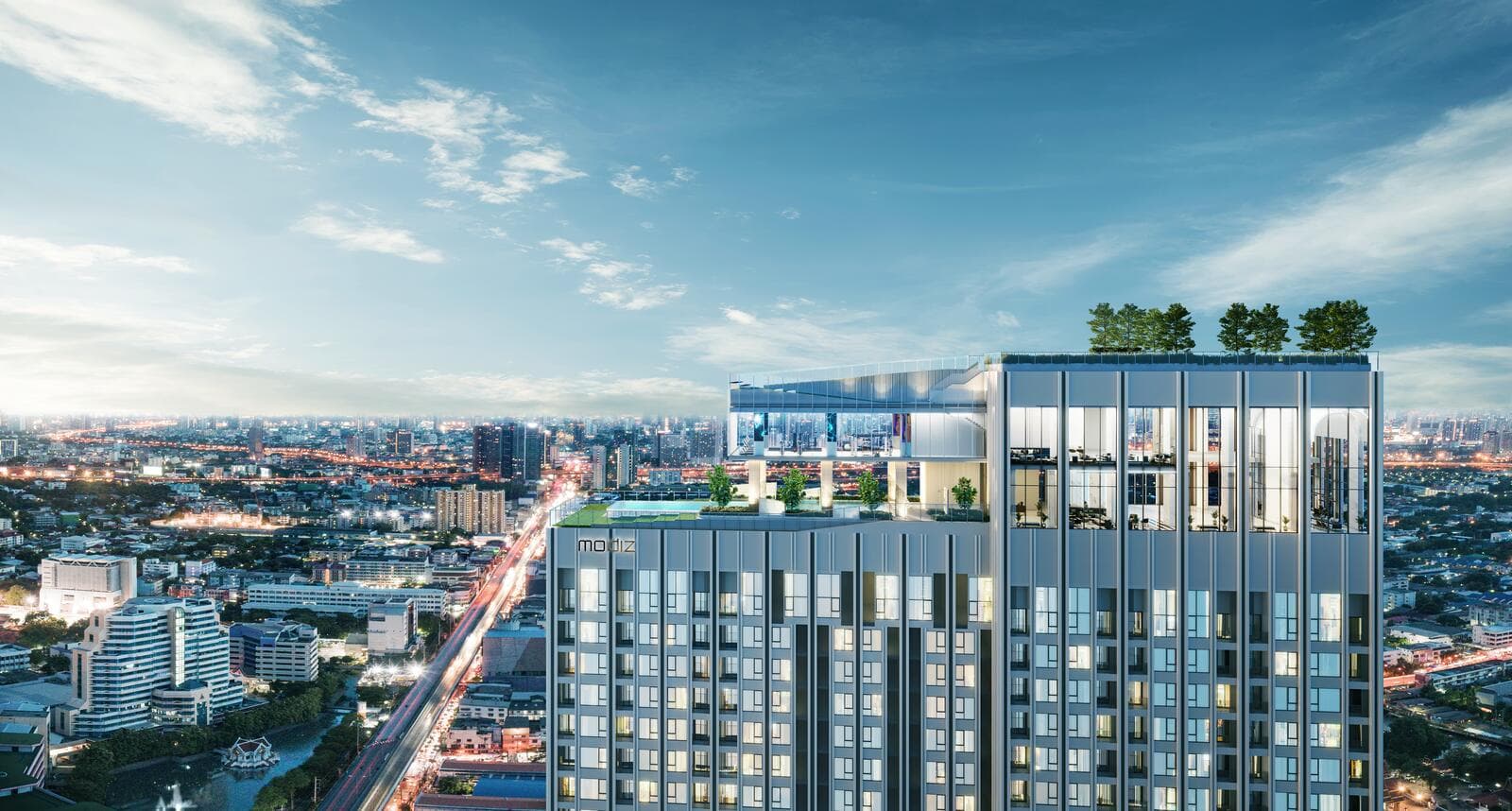 Twilight view of the upper floors and rooftop crown of Modiz Rhyme Ramkhamhaeng, showing the double-height glazed sky lounge, rooftop garden trees and pool deck above the tower with the Bangkok skyline stretching to the horizon (computer-generated render)