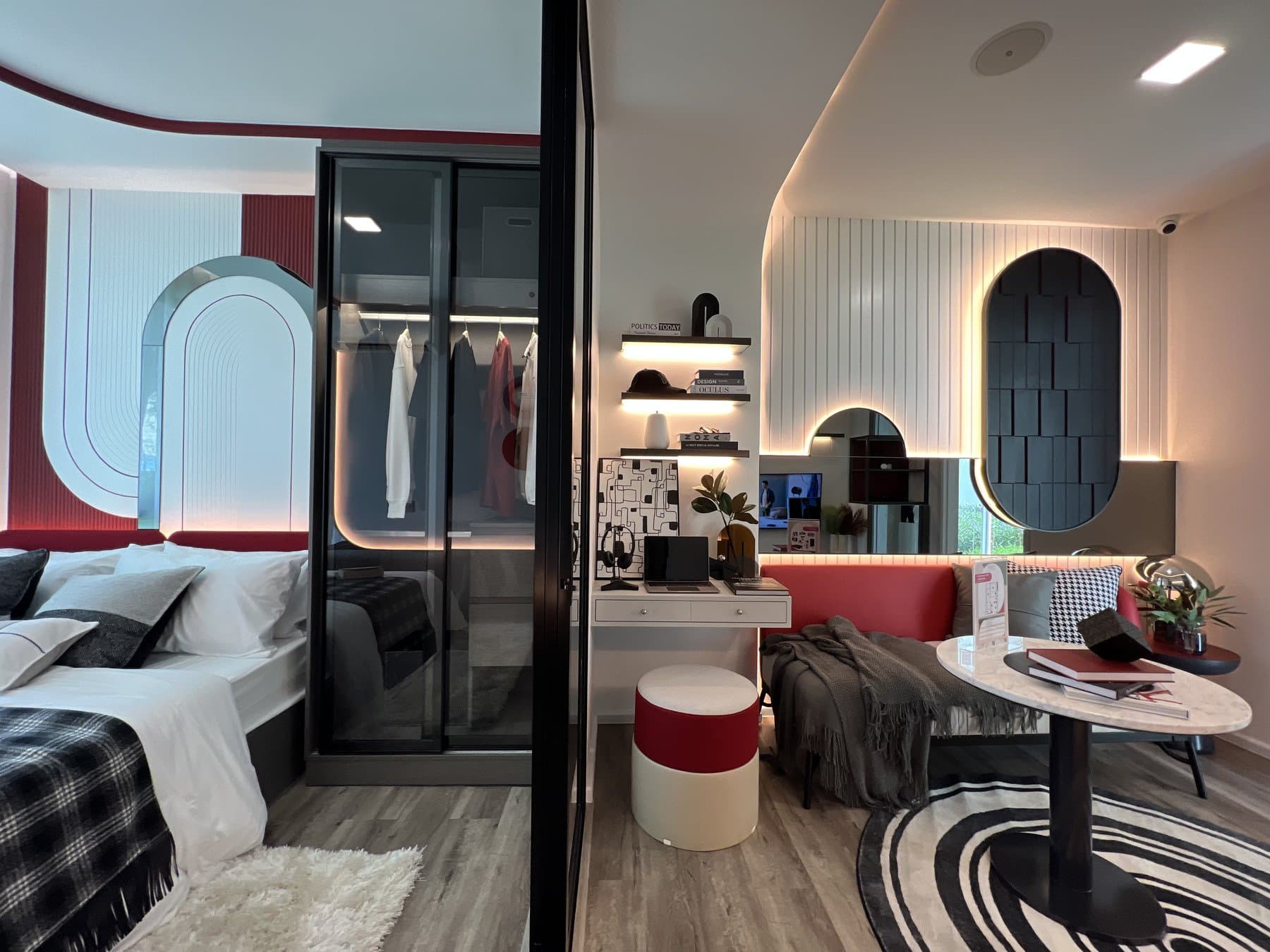 Bedroom and mirrored wardrobe in a furnished show unit at Modiz Vault, with a red arch detail and a chequered throw on the bed