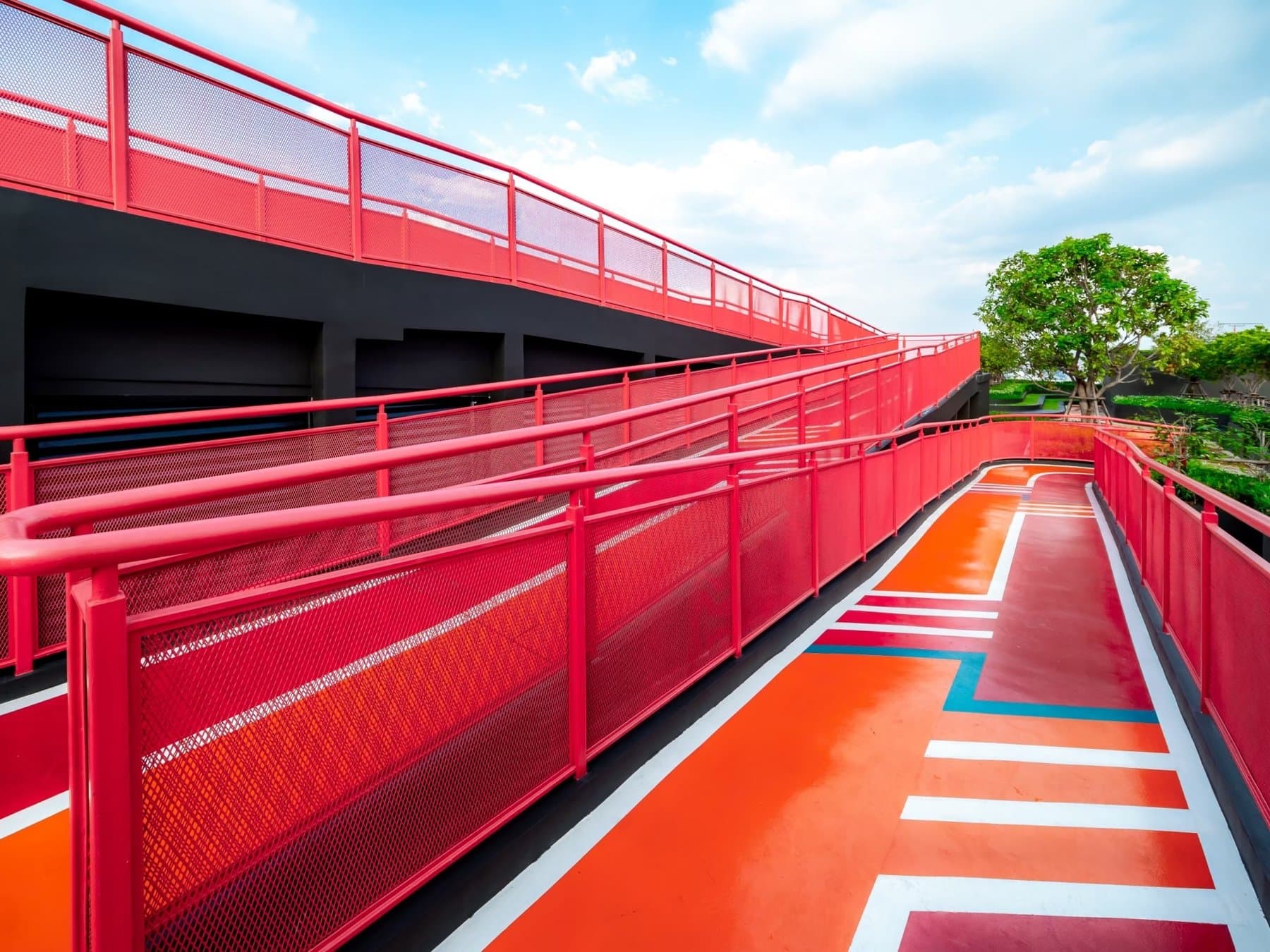 Rooftop running track at Origin Plug & Play Nonthaburi Station, marked in orange and white with red mesh balustrades and a tree in a raised planter