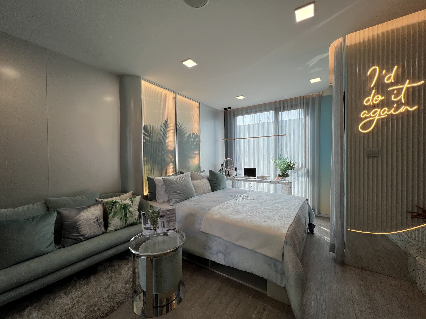 Bedroom of a furnished show unit at Atmoz Oasis Onnut, with fluted timber panelling, a neon script sign above the bed and a mirrored side table