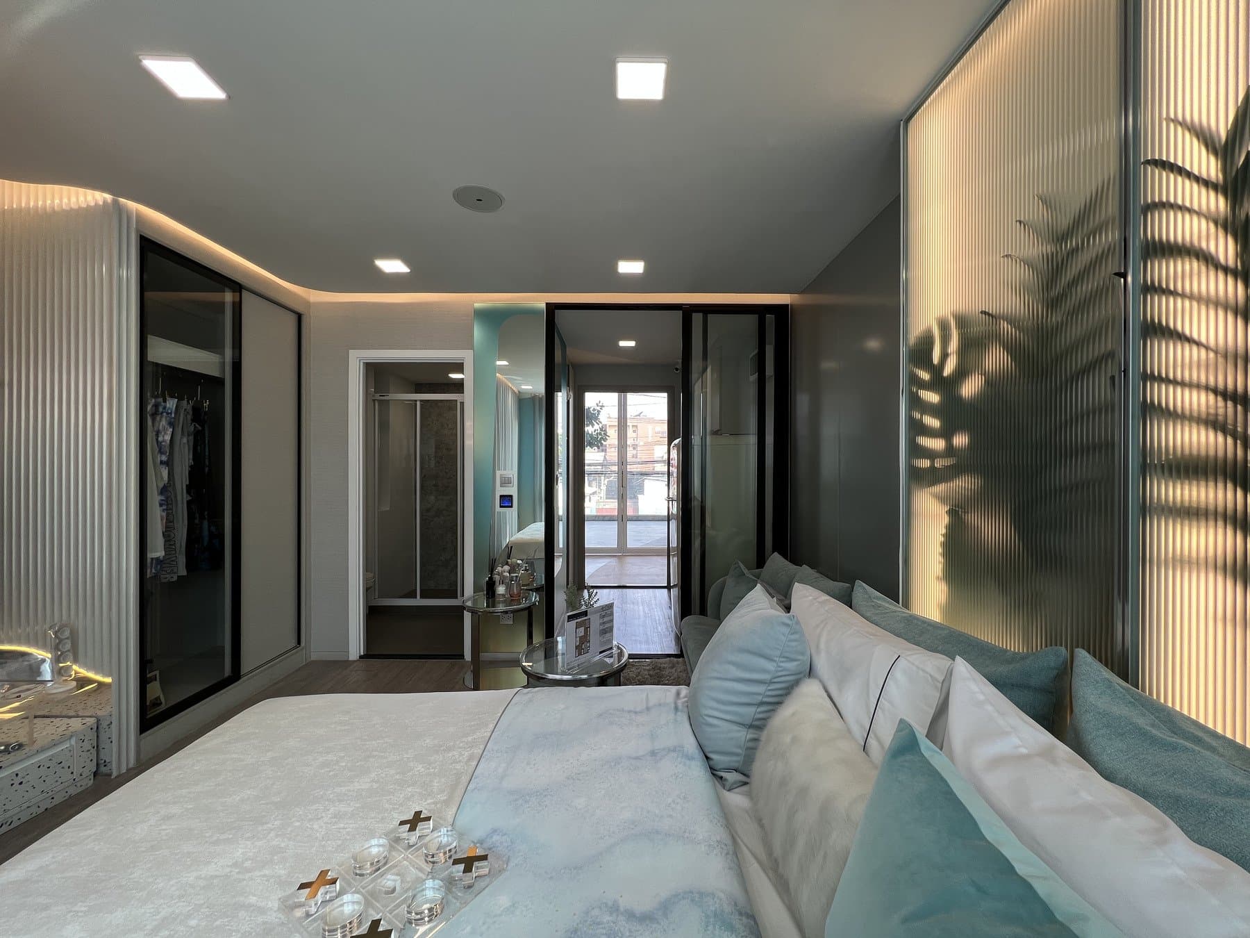 Furnished show unit at Atmoz Oasis Onnut looking from the bed toward the dark mirrored wardrobe and the entrance corridor