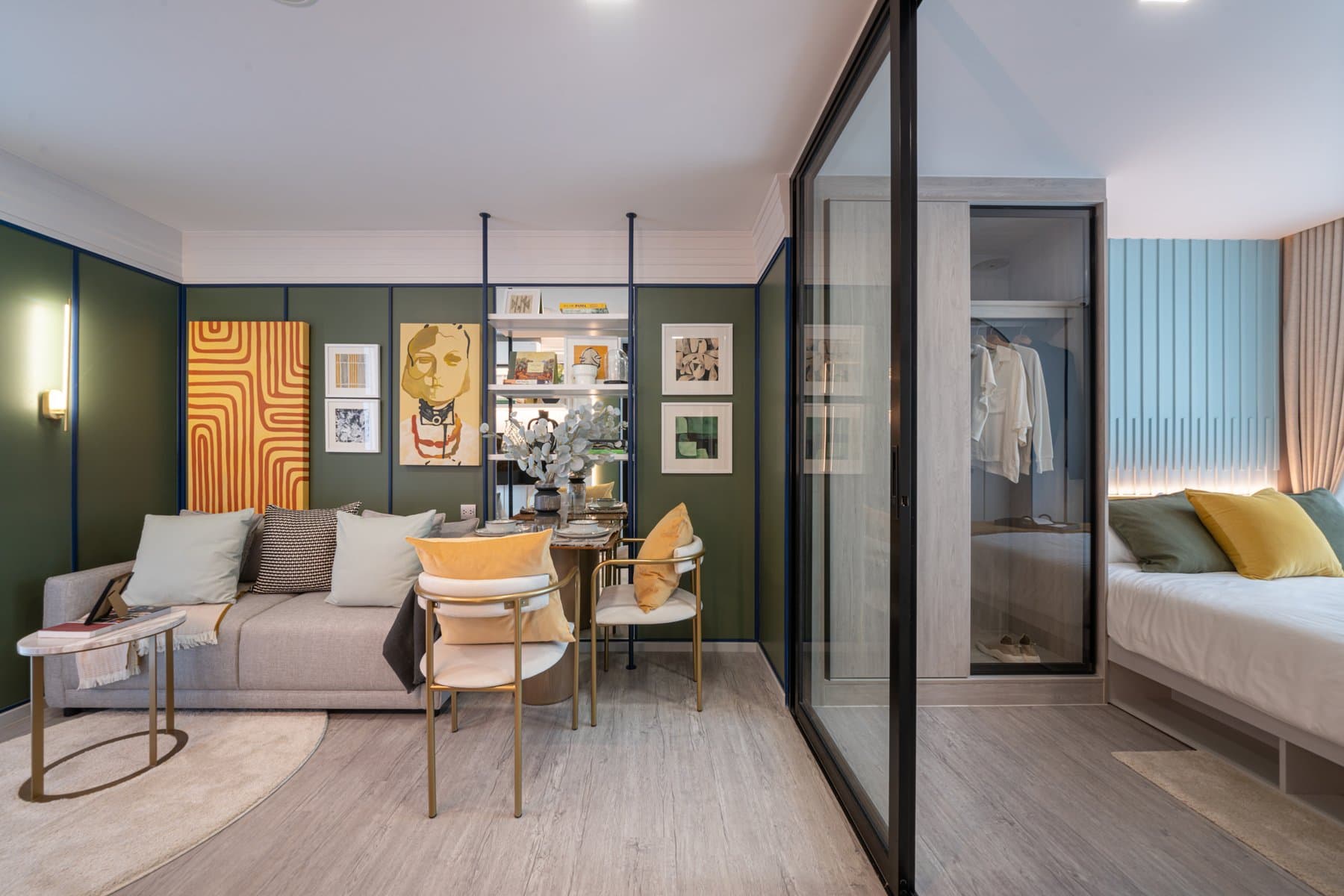 Full length of a furnished show unit at Atmoz Portrait Srisaman, from the green-panelled living wall through the glazed partition to the bedroom
