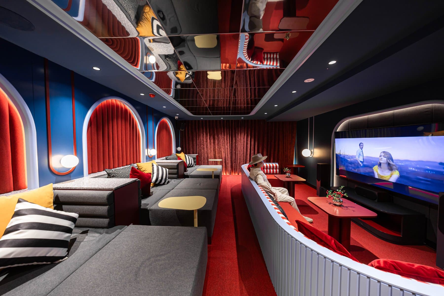 Karaoke and screening room at Kave COCO Bangsaen, with curved red banquette seating, arched alcoves and a wall-mounted screen
