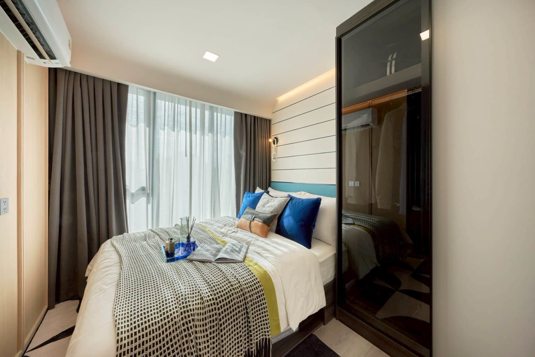 One Bedroom Exclusive bedroom at Kave Genesis looking toward the curtained window, with a mirrored wardrobe running the length of the wall